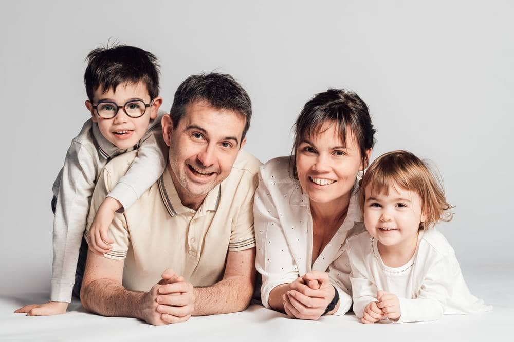 Portrait de famille de 4 personnes allonger sur un fond blanc en studio