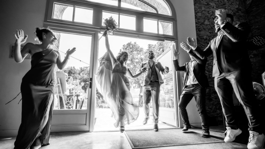 couple de mariés qui rentre dans leur salle de reception en sautant